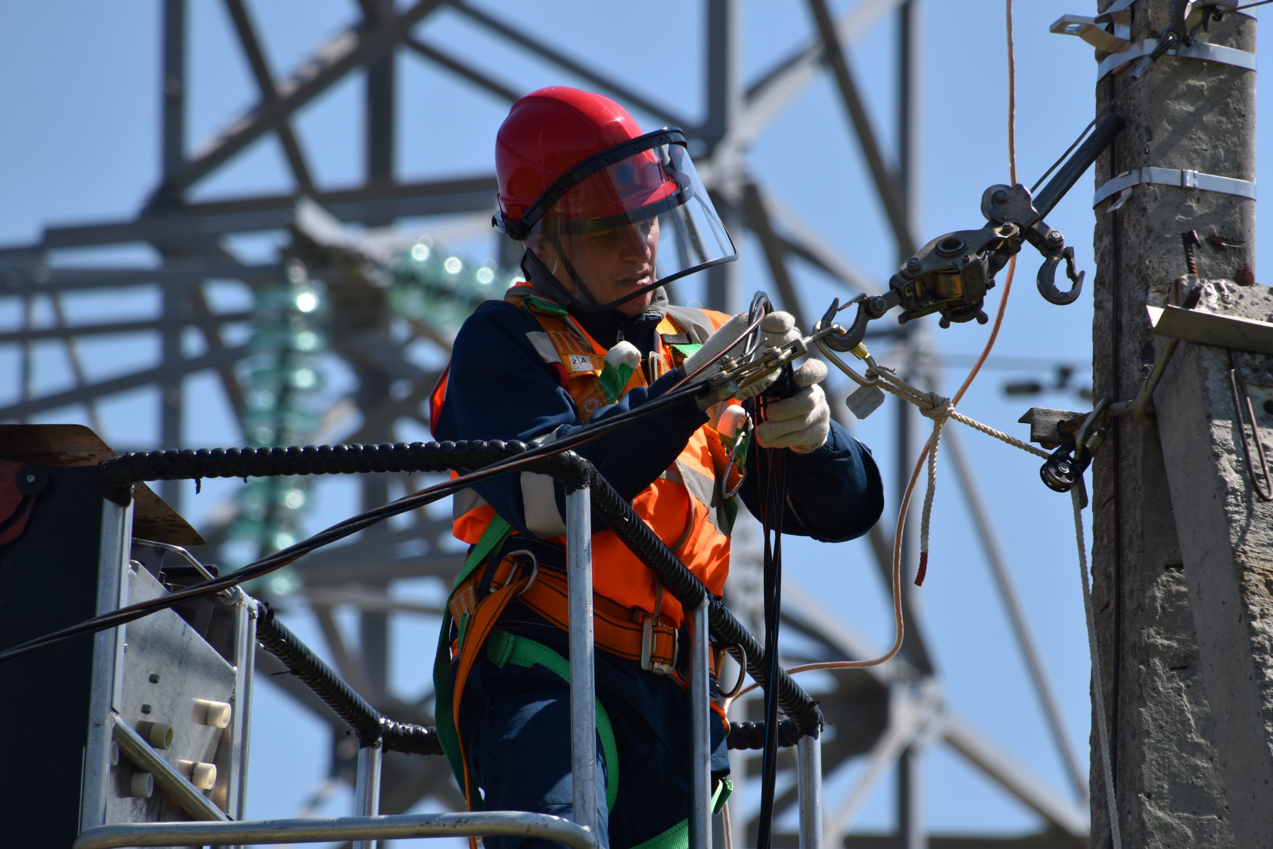 imagem de um homem fazendo uma instalação elétrica complexa no alto de um poste, representando uma instalação elétrica industrial.