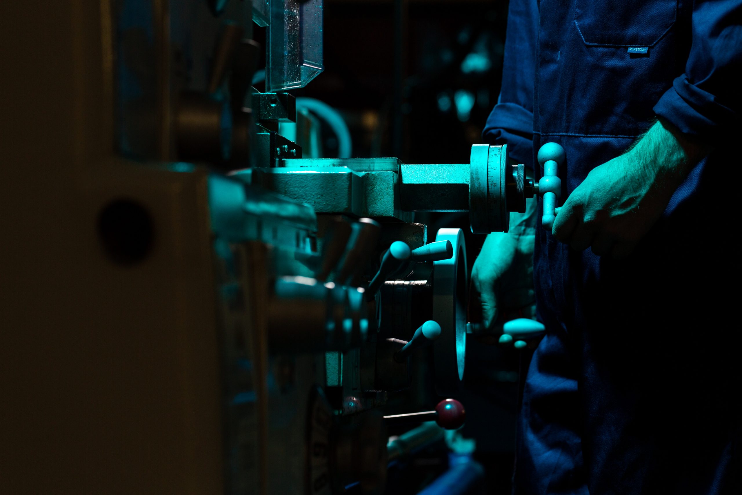 imagem de um homem realizando ajustes mecânicos em uma máquina pesada de uma grande indústria